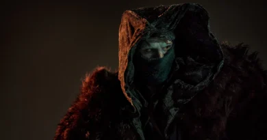 O monstro de Frankenstein vivido por Jacob Elordi em cena do filme de Guillermo del Toro, com iluminação dramática em tons de laranja e vermelho contra fundo escuro, mostrando detalhes da criatura com expressão intensa e atmosfera cinematográfica sombria.