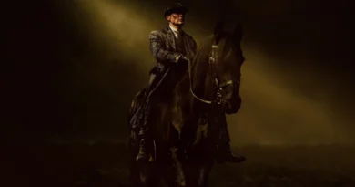 Pôster promocional do filme Peaky Blinders: O Homem Imortal, com Cillian Murphy como o protagonista Tommy Shelby. Ele está montado em um imponente cavalo preto em um terreno escuro e acidentado, olhando para a frente com uma expressão intensa e resoluta. Tommy veste seu traje clássico de Peaky Blinder, incluindo um sobretudo pesado, terno de tweed e a icônica boina (flat cap). Um feixe de luz dourada dramática brilha de cima através da fumaça e névoa escura, iluminando o personagem e a cabeça do cavalo contra um fundo sombrio e atmosférico. Capa da crítica do filme no blog Multi Nerdz.