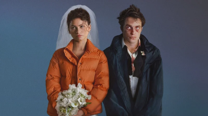 Um retrato de estúdio em plano médio de Zendaya e Robert Pattinson como seus personagens no filme O Drama. Zendaya, à esquerda, usa um vestido de noiva branco e véu, coberto por uma jaqueta puffer laranja brilhante, segurando um buquê de flores brancas com uma expressão séria e angustiada. Robert Pattinson, à direita, veste um terno preto desarrumado com camisa social branca manchada de sangue e gravata solta, coberto por uma jaqueta esportiva azul marinho. Seu rosto está visivelmente machucado, com hematomas e sangue. Ambos têm expressões melancólicas e olham para a frente. O fundo é um gradiente suave de azul para roxo-azulado. Capa da crítica do filme no blog Multi Nerdz.