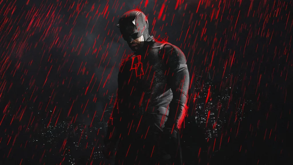 Pôster da segunda temporada da série Demolidor: Renascido, destacando o ator Charlie Cox como o herói Demolidor. Ele está no centro da imagem em uma pose sombria e imponente, com a cabeça levemente abaixada. O personagem veste um traje tático escuro e texturizado, incluindo o clássico capacete com pequenos chifres que cobre a parte superior do seu rosto, deixando apenas o queixo com barba por fazer à mostra. No peito do traje, brilha um emblema com as letras "DD" em neon vermelho. O cenário de fundo é escuro, revelando a silhueta de uma cidade à noite com algumas janelas de prédios acesas. Um efeito visual dramático mostra uma forte chuva caindo, mas as gotas de água são de um tom vermelho vivo e brilhante, criando reflexos avermelhados na silhueta do herói, como se fosse sangue. Capa da crítica da série no blog Multi Nerdz.