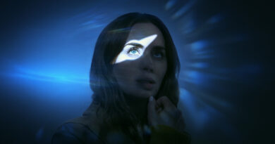 Emily Blunt em cena de Dia D, filme dirigido por Steven Spielberg, com iluminação azul e feixe de luz destacando seu olhar em meio a um ambiente escuro e enigmático. A atriz demonstra expressão séria e reflexiva em uma das cenas do longa. Imagem de destaque da crítica do filme no Multi Nerdz.