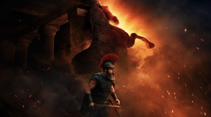 Matt Damon caracterizado como Odisseu, usando armadura e capacete com crista vermelha enquanto segura uma espada diante do Cavalo de Troia em chamas, na capa da crítica de ‘A Odisseia’ no blog Multi Nerdz.