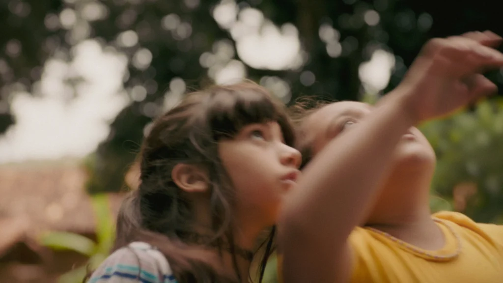 Laura Brandão como Glória e Serena como Sofia aparecem juntas ao ar livre, olhando para cima e apontando para algo fora de cena, em imagem do filme ‘A Natureza das Coisas Invisíveis’.