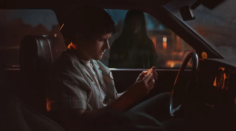 Capa da crítica de ‘Obsessão’ no blog Multi Nerdz, com Michael Johnston como Bear sentado dentro de um carro, observando o objeto sobrenatural One Wish Willow em suas mãos, enquanto a silhueta de Inde Navarrette como Nikki aparece do lado de fora da janela. A iluminação noturna em tons azulados e alaranjados reforça o clima sombrio e inquietante do filme.